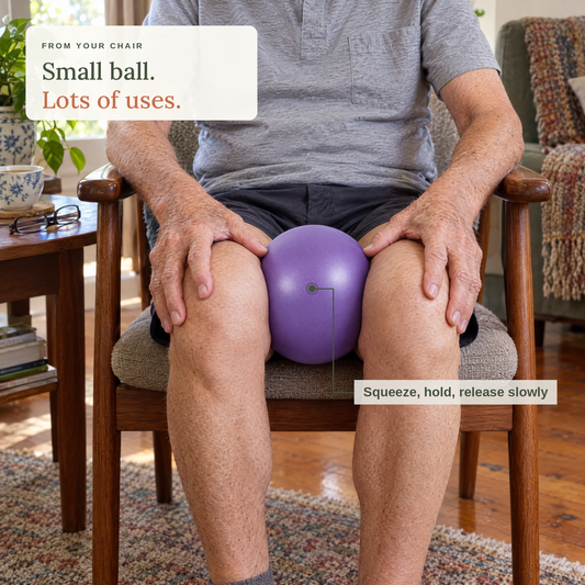 Older man seated in a timber armchair squeezing the purple ball between his knees