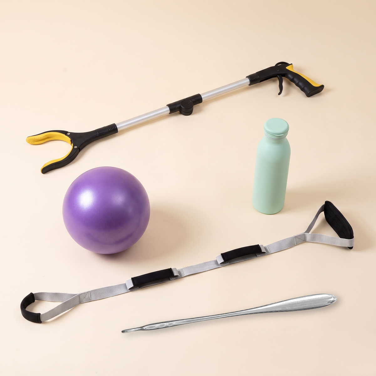 Hip Replacement Ready Kit — folding grabber, triple grip leg lifter, 52cm steel shoe horn, mini exercise ball and insulated bottle on a cream background