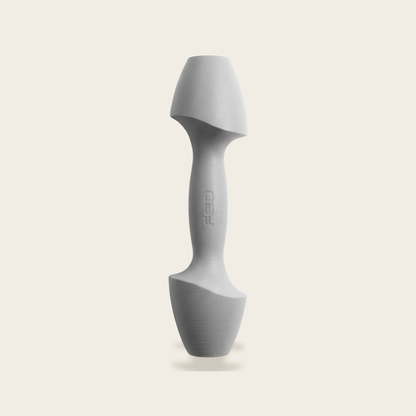 The Sculpt Dumbbell in grey on a cream background