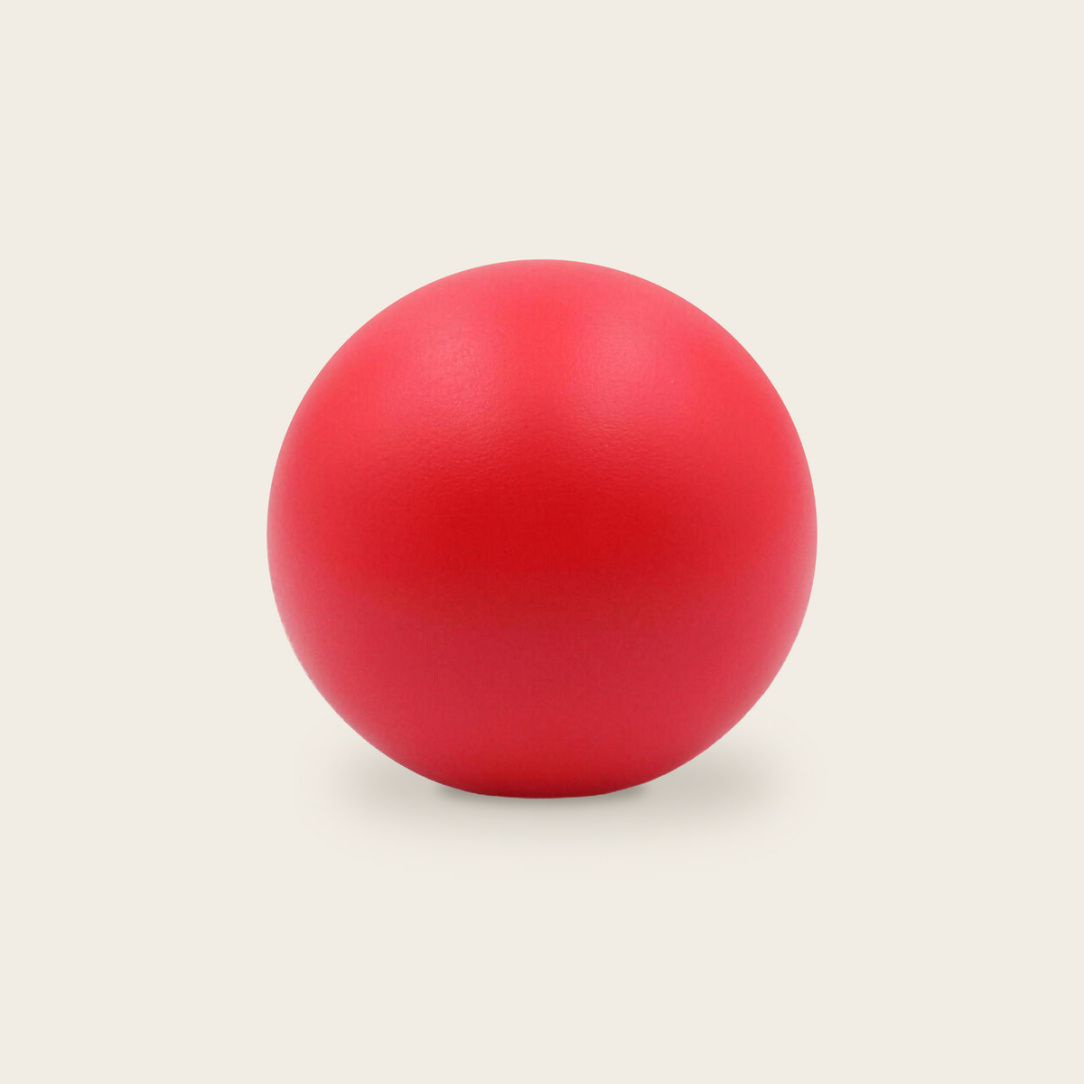 Soft grip strength ball in red on a cream background