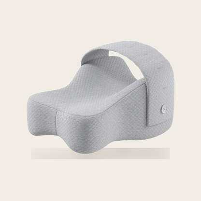 Orthopaedic knee pillow in grey with adjustable strap on a cream background