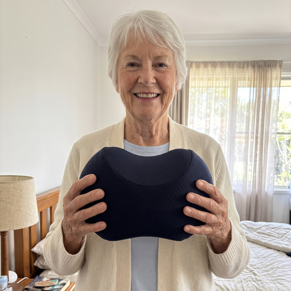 Woman holding the Bean Knee Pillow in her bedroom