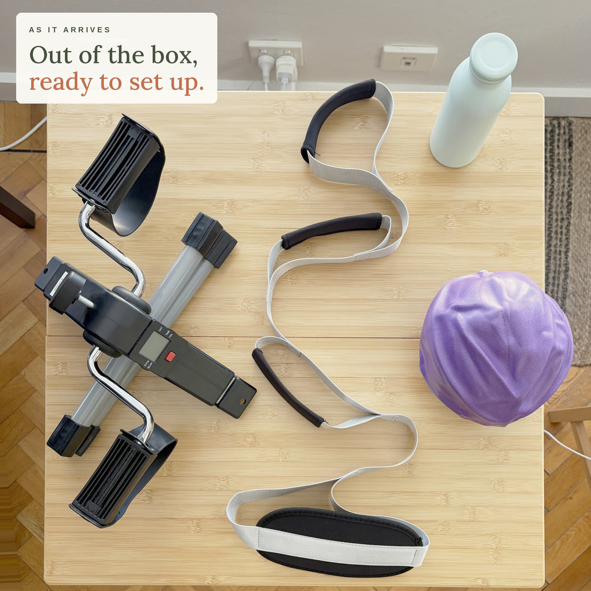 As it arrives. Out of the box, ready to set up: the Knee Replacement Ready Kit on a kitchen table seen from above, with the mini pedal exerciser, leg lifter, mini exercise ball and bottle