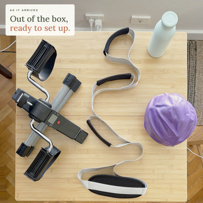 As it arrives. Out of the box, ready to set up: the Knee Replacement Ready Kit on a kitchen table seen from above, with the mini pedal exerciser, leg lifter, mini exercise ball and bottle