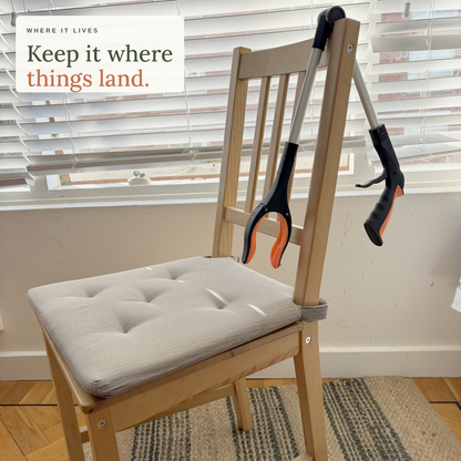 Keep it where things land: the orange foldable long reach grabber folded over the back of a dining chair at home