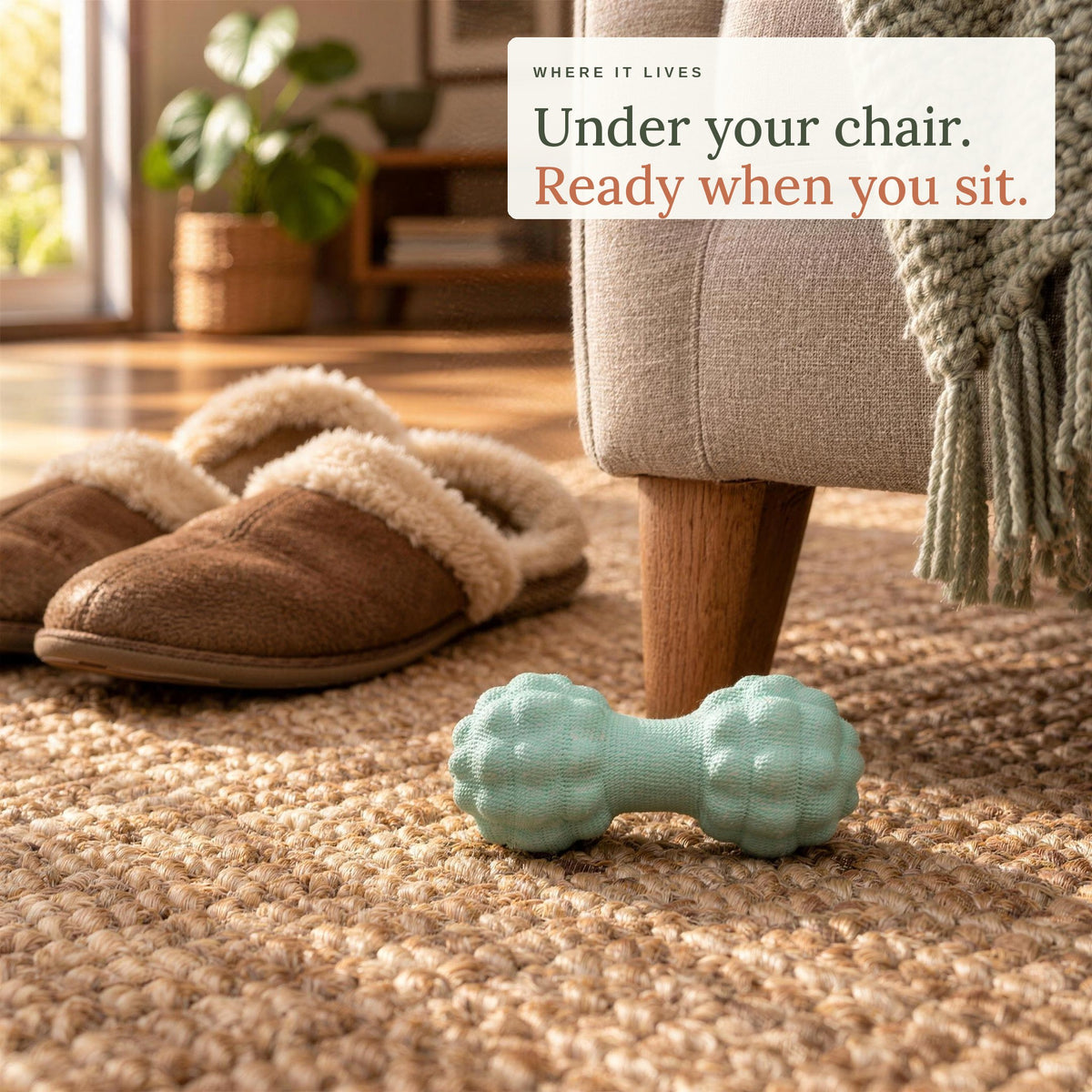 The Peanut Massage Ball on a jute rug beside an armchair and slippers